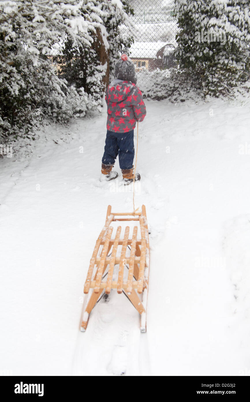 Trois ans à l'extérieur de jouer dans la neige sur un toboggan. Alresford Hampshire, Angleterre, Royaume-Uni. Banque D'Images