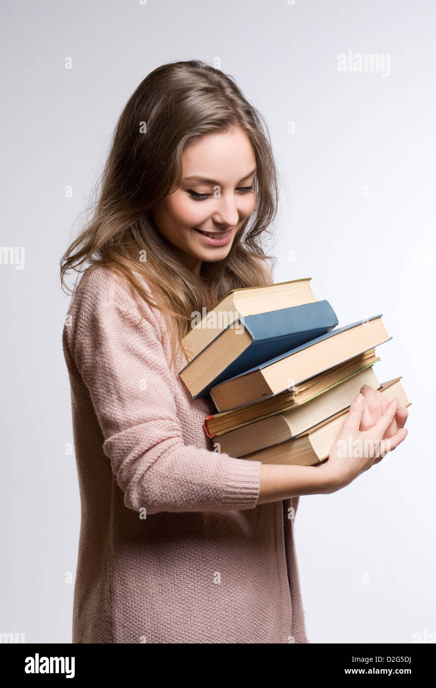 Portrait d'une jeune brunette de rêve student holding beaucoup de livres. Banque D'Images