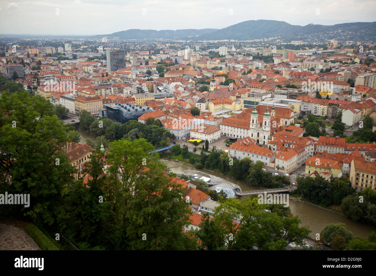 Vue panoramique de Graz, Autriche, mettant en valeur les toits rouges emblématiques de la ville, son architecture historique et les collines luxuriantes environnantes sous un ciel nuageux Banque D'Images
