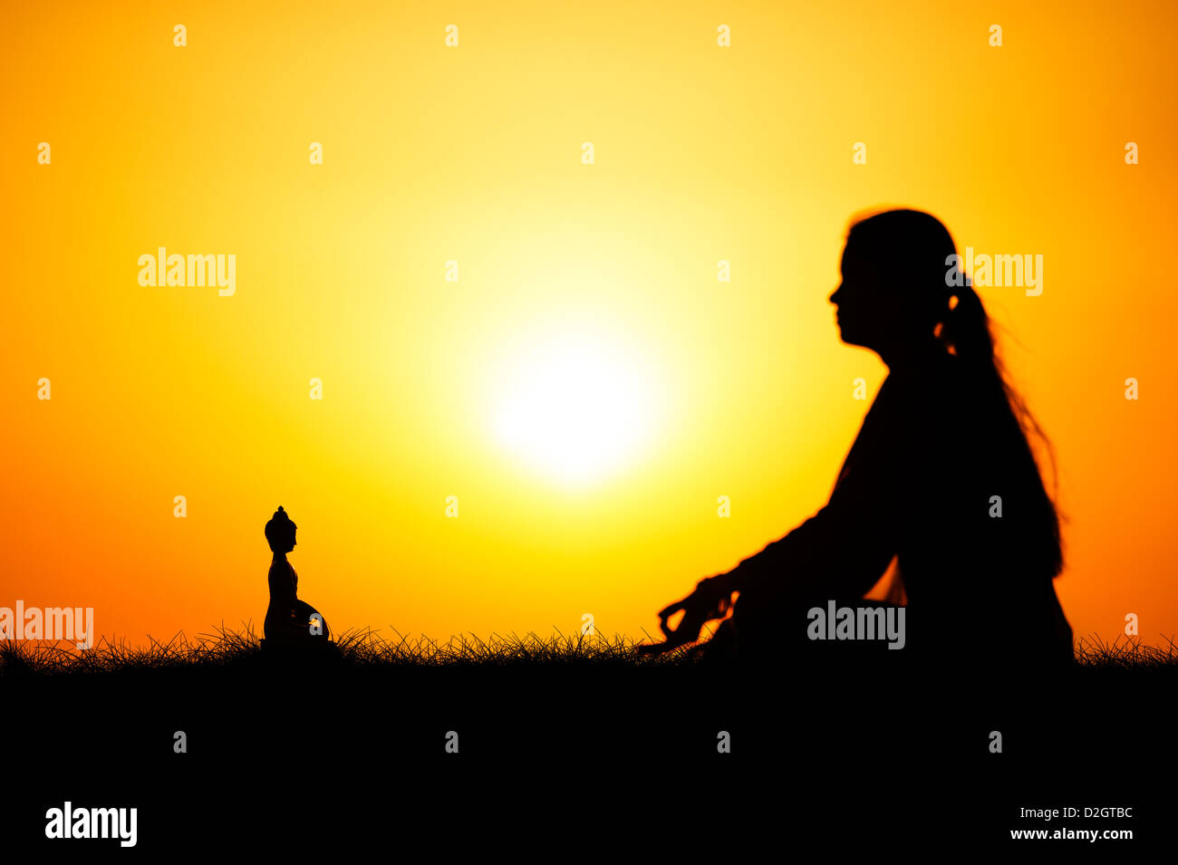 Sunset silhouette d'une jeune Indienne méditer en face de statue de Bouddha. L'Andhra Pradesh, Inde Banque D'Images