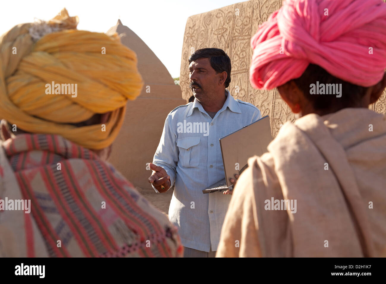 L'Inde, Rajasthan, désert du Thar, maire de district de visiter les villageois et holding laptop Banque D'Images