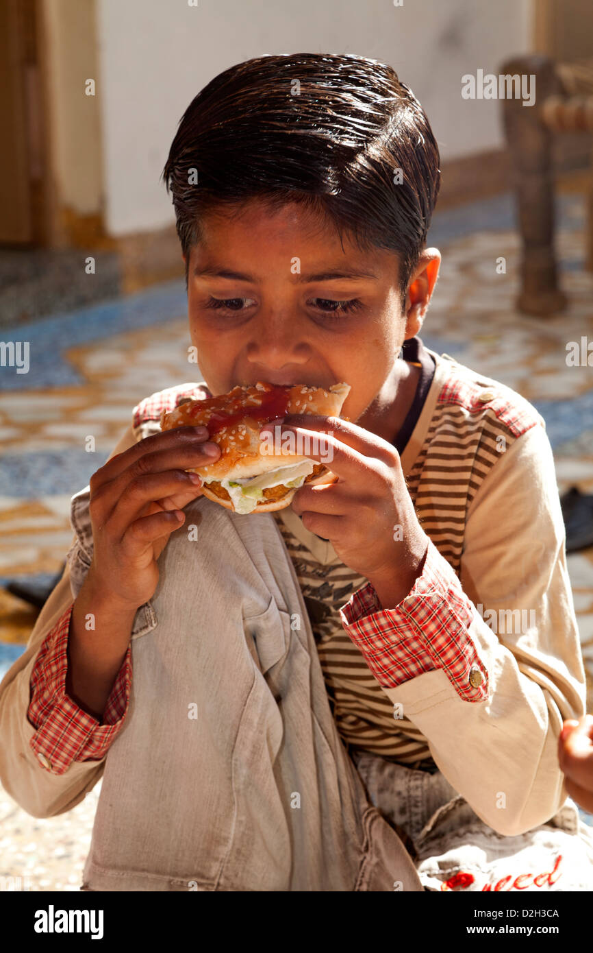 L'Inde, Uttar Pradesh, Agra Indian boy eating fast food western Banque D'Images