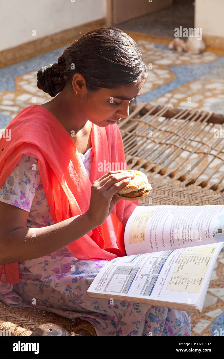 L'Inde, Uttar Pradesh, Agra Indian girl eating fast food style occidental alors que l'étude Banque D'Images