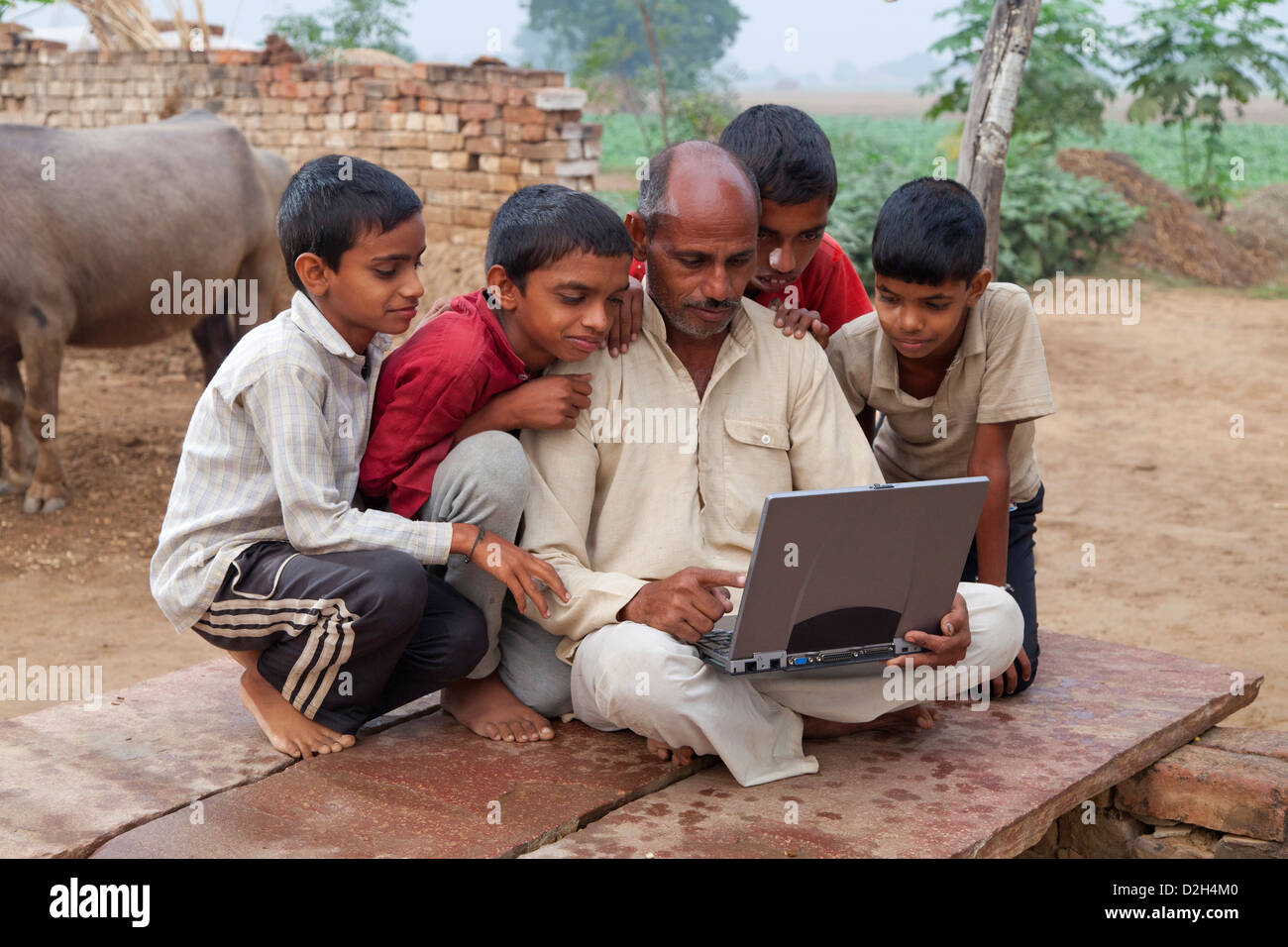 L'Inde, Uttar Pradesh, quatre enfants du village et père looking at laptop computer Banque D'Images