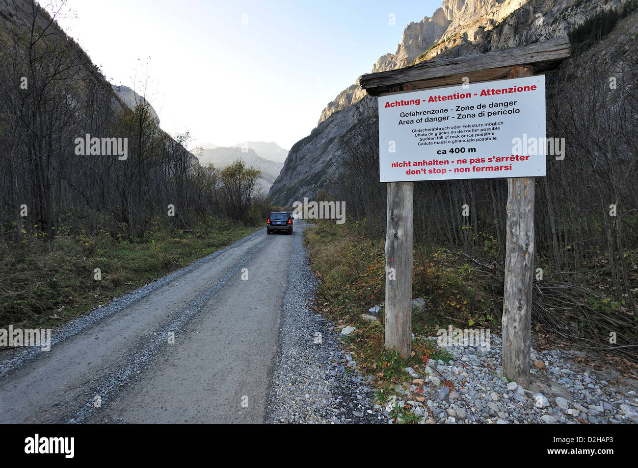 Une route de gravier dans les Alpes suisses qui est passible d'éboulements. Inscrivez-vous prévient les conducteurs de ne pas s'arrêter. Banque D'Images