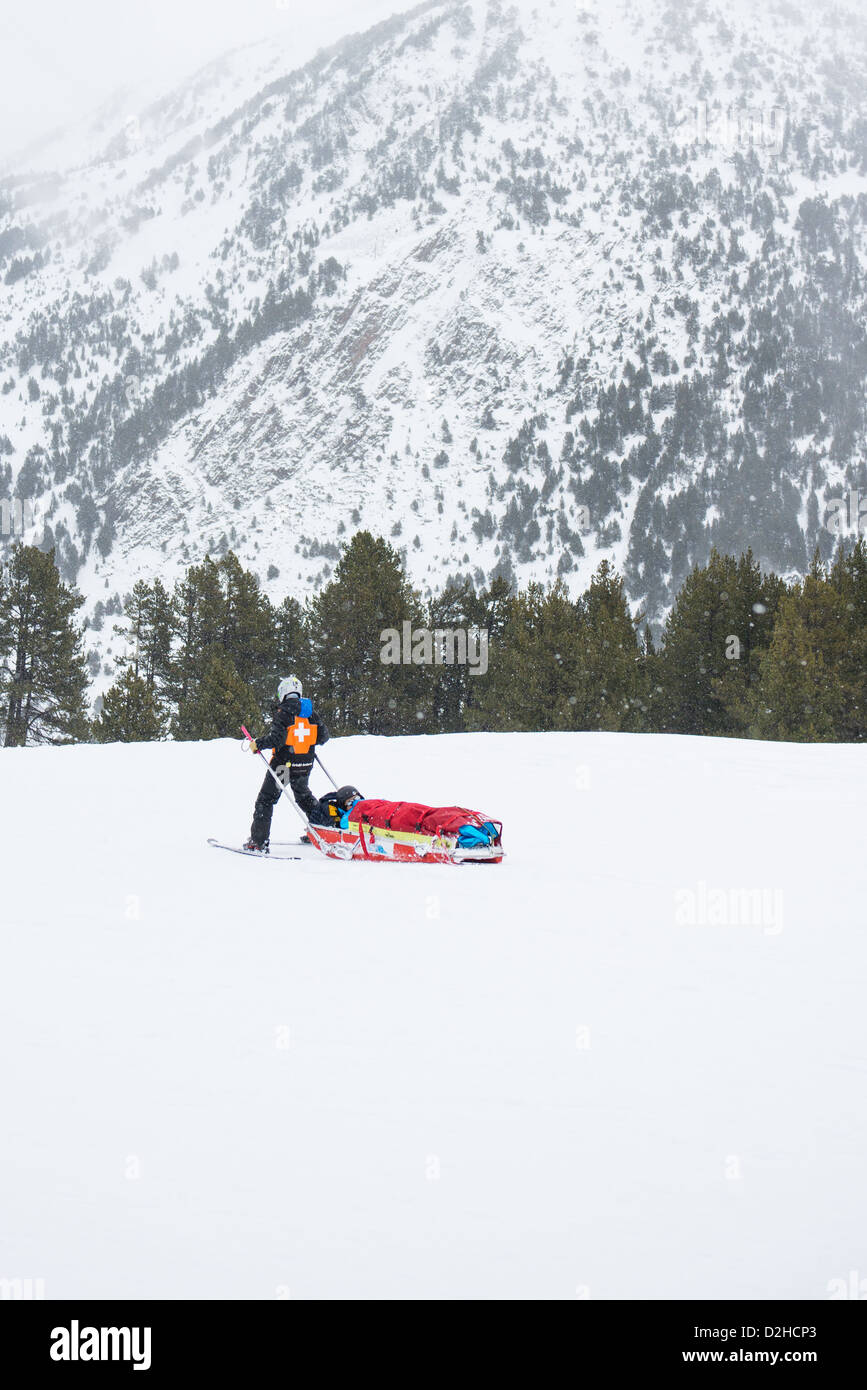 Ski alpin de sauvetage dans les Pyrénées d'Andorre. Un skieur blessé retourne au centre médical par une patrouille de neige médic attaché dans un traîneau. Banque D'Images