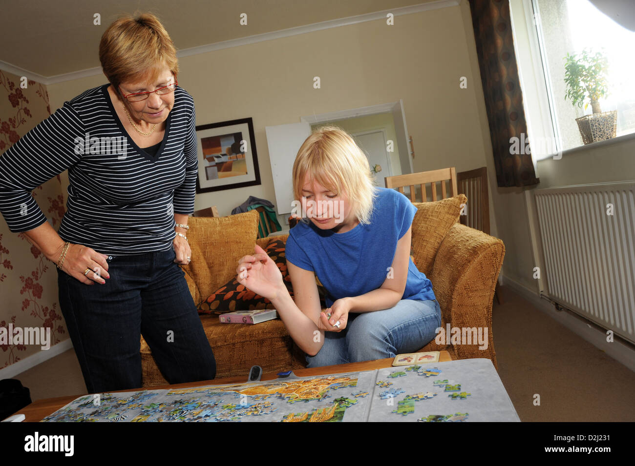 Une des jeunes femmes ayant des troubles d'apprentissage bénéficie d'faire un puzzle denteux avec son soutien à la personne, Skipton, Yorkshire du Nord. Banque D'Images