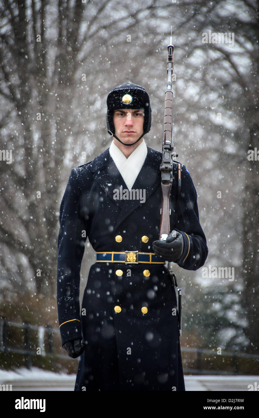 Tombeau du soldat inconnu Sentinel Arlington Virginie // ARLINGTON, Virginie — Un soldat monte la garde au tombeau des inconnus au cimetière national d'Arlington pendant les chutes de neige. La sentinelle du 3rd U.S. Infantry Regiment maintient la veille cérémonielle malgré les conditions météorologiques hivernales. Le garde suit une routine précise de 21 étapes, marchant le long du tapis noir derrière la tombe avant de tourner et de faire face à l'est pendant 21 secondes, puis au nord pendant 21 secondes. La tombe du soldat inconnu est gardée en permanence 24 heures sur 24, 365 jours par an depuis 1937. Banque D'Images