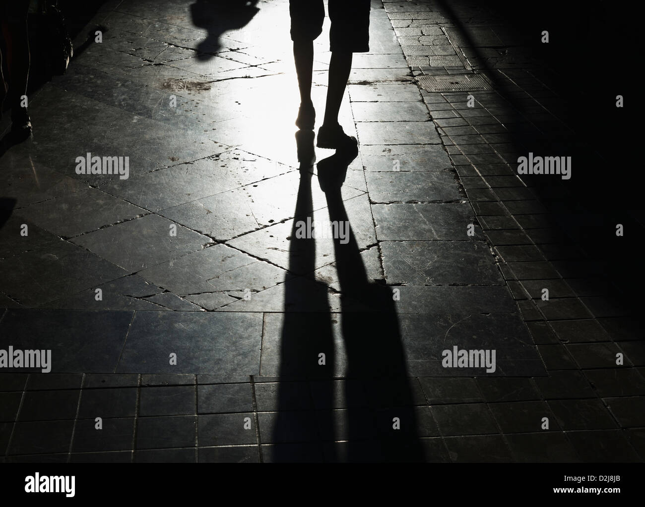 Une personne marchant sur un chemin lumineux avec leur ombre derrière eux ; malaga costa del sol andalousie espagne Banque D'Images