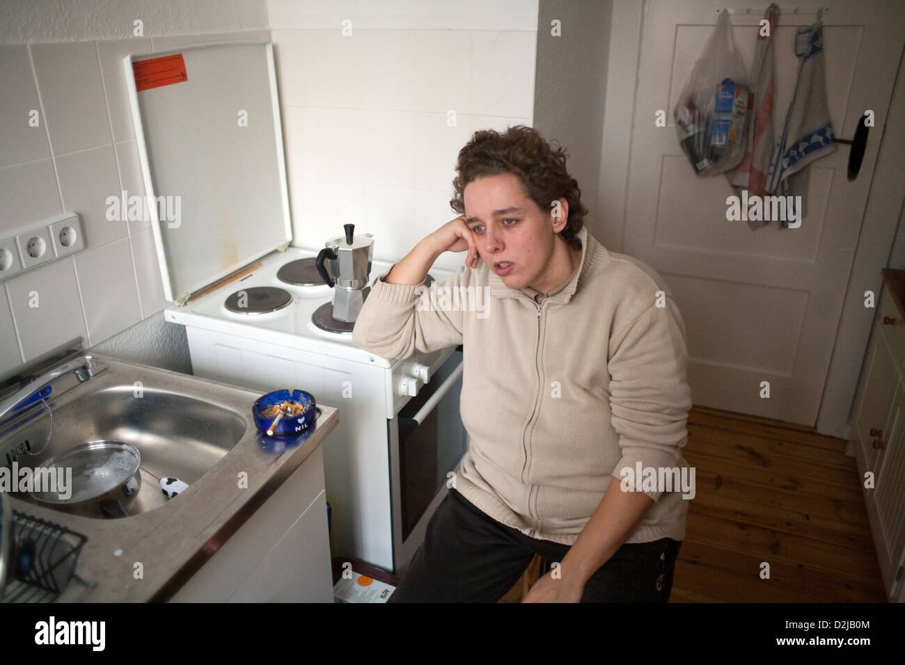 Berlin, Allemagne, une femme assise listlessly dans sa cuisine Banque D'Images