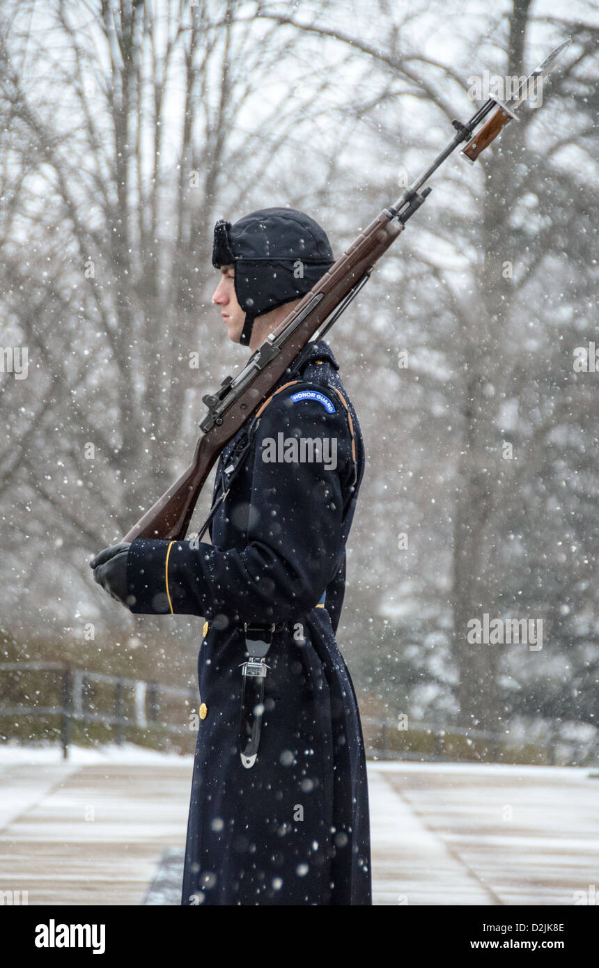 Tombeau du soldat inconnu Sentinel Arlington Virginie // ARLINGTON, Virginie — Un soldat monte la garde au tombeau des inconnus au cimetière national d'Arlington pendant les chutes de neige. La sentinelle du 3rd U.S. Infantry Regiment maintient la veille cérémonielle malgré les conditions météorologiques hivernales. Le garde suit une routine précise de 21 étapes, marchant le long du tapis noir derrière la tombe avant de tourner et de faire face à l'est pendant 21 secondes, puis au nord pendant 21 secondes. La tombe du soldat inconnu est gardée en permanence 24 heures sur 24, 365 jours par an depuis 1937. Banque D'Images