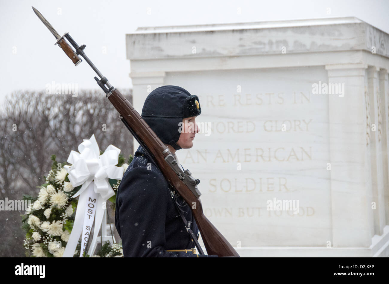Tombeau du soldat inconnu Sentinel Arlington Virginie // ARLINGTON, Virginie — Un soldat monte la garde au tombeau des inconnus au cimetière national d'Arlington pendant les chutes de neige. La sentinelle du 3rd U.S. Infantry Regiment maintient la veille cérémonielle malgré les conditions météorologiques hivernales. Le garde suit une routine précise de 21 étapes, marchant le long du tapis noir derrière la tombe avant de tourner et de faire face à l'est pendant 21 secondes, puis au nord pendant 21 secondes. La tombe du soldat inconnu est gardée en permanence 24 heures sur 24, 365 jours par an depuis 1937. Banque D'Images