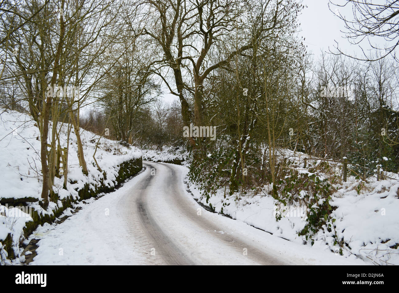 Country Lane sur Bend Lancashire/Yorkshire Border sous la neige et la glace en hiver Banque D'Images