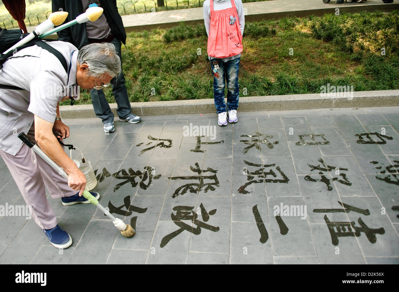 Un homme écrit un script chinois sur le trottoir, Beijing, Chine Banque D'Images