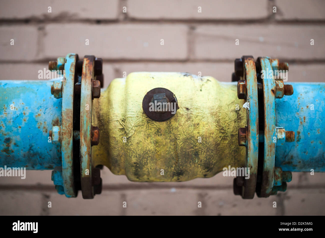 Vieille tuyauterie de gaz au-dessus du mur de briques gris connexion Banque D'Images