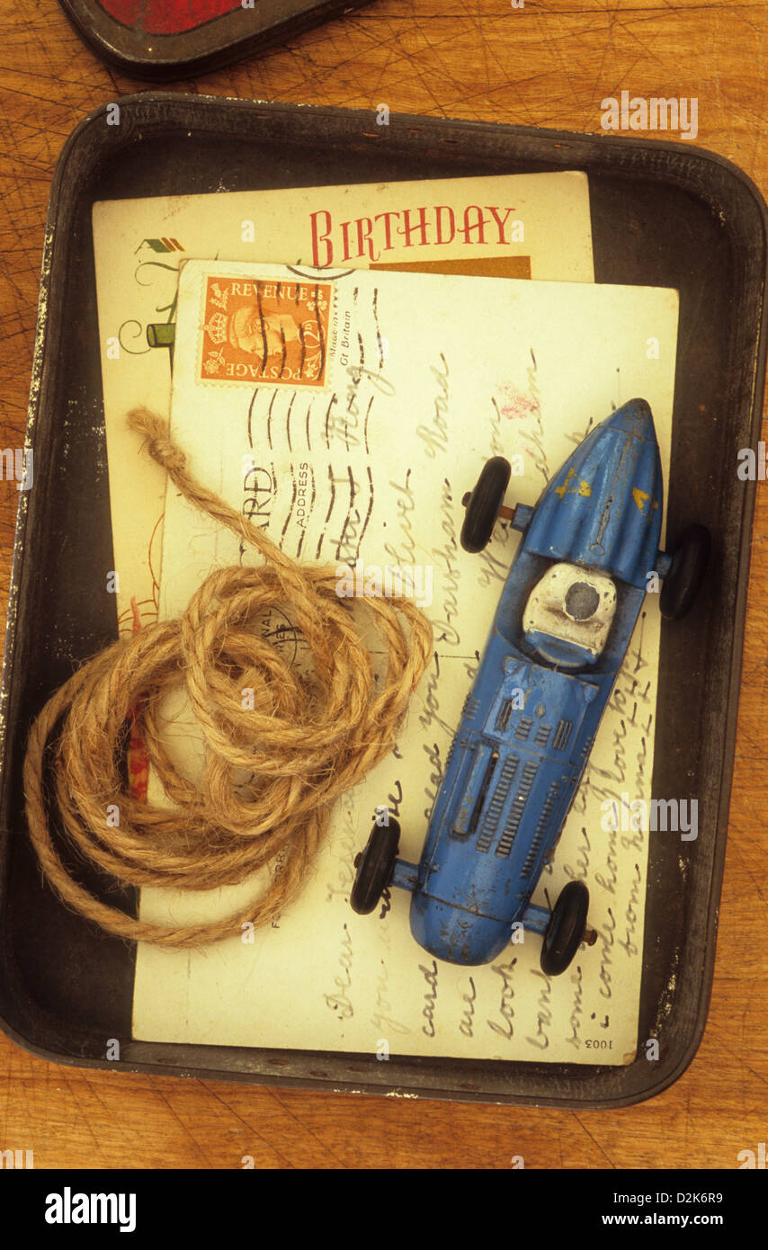Petite boîte contenant 1940 carte postale et carte d'anniversaire modèle de plomb battue et voiture de course avec la bobine de ficelle Banque D'Images