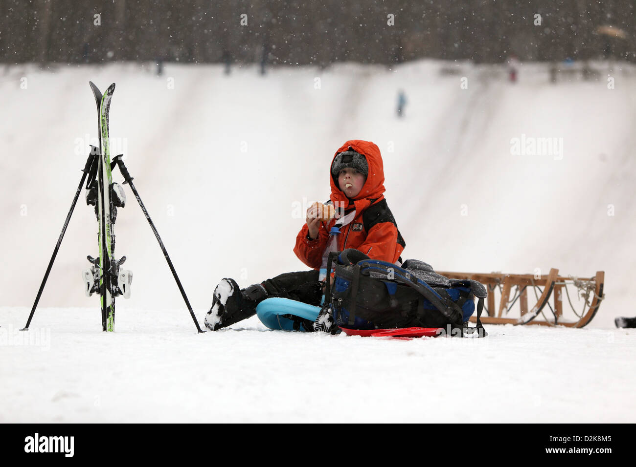Berlin, Allemagne, garçon assis dans la neige fait une pause après les sports d'hiver Banque D'Images