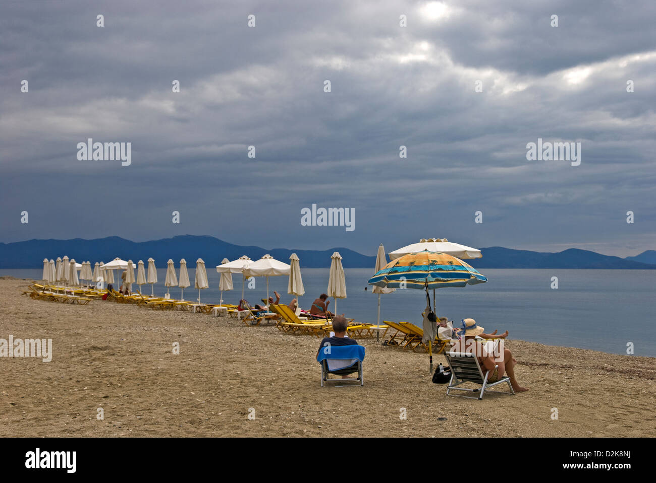 Rangée de chaises de plage et parasols sur un jour nuageux à la plage Banque D'Images