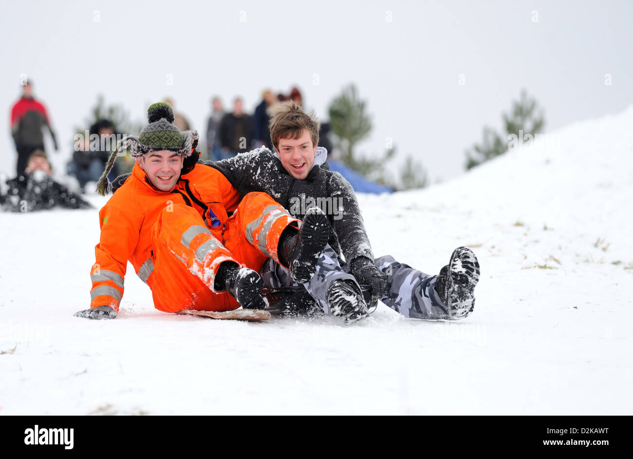 Deux jeunes hommes bénéficiant de la luge ensemble sur une colline couverte de neige par une froide journée de l'hiver. Banque D'Images