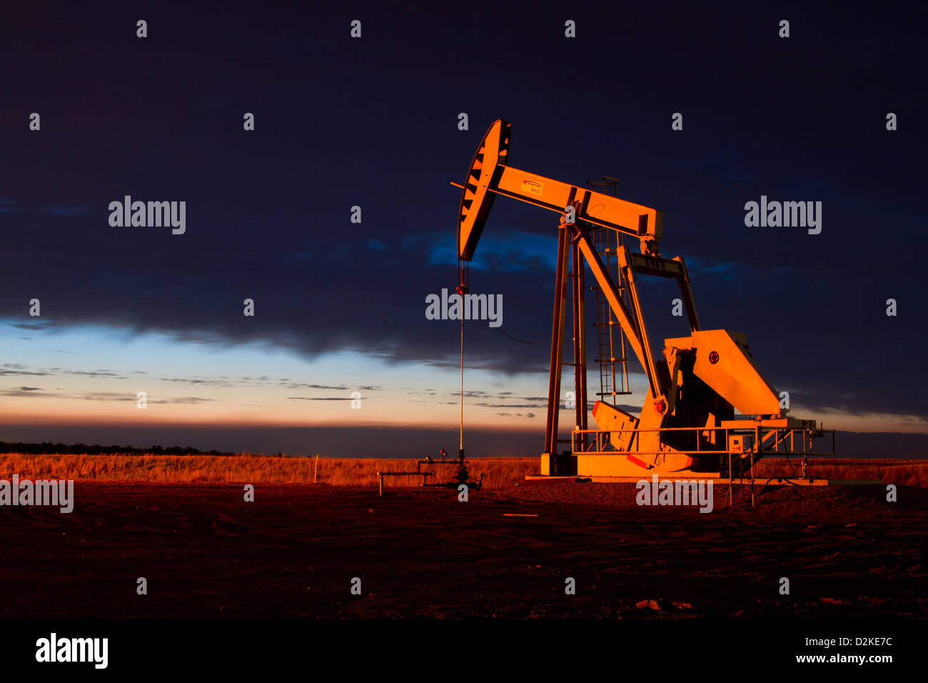 Une flamme de gaz naturel peint le côté de la pompe d'un puits de pétrole jack orange comme la nuit tombe dans la zone pétrolière de Bakken champs dans ND. Banque D'Images