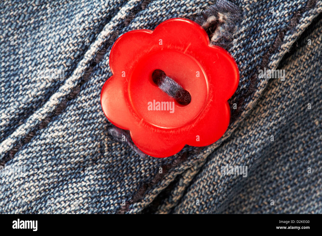 bouton rouge en forme de fleur sur la robe en jean pour petite fille Banque D'Images