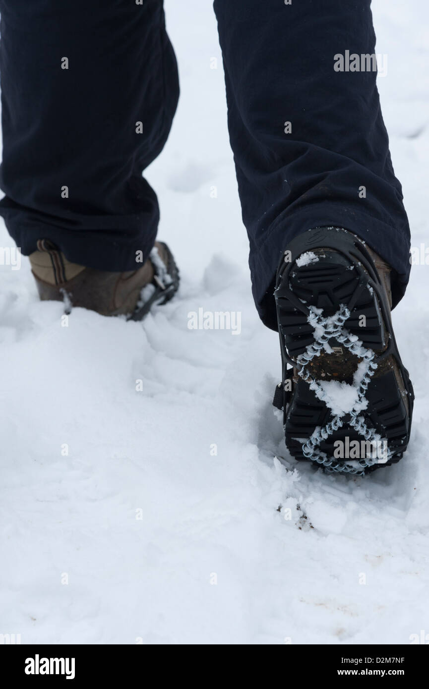 Pinces de glace sur une personne portant des bottes dans la neige. Banque D'Images