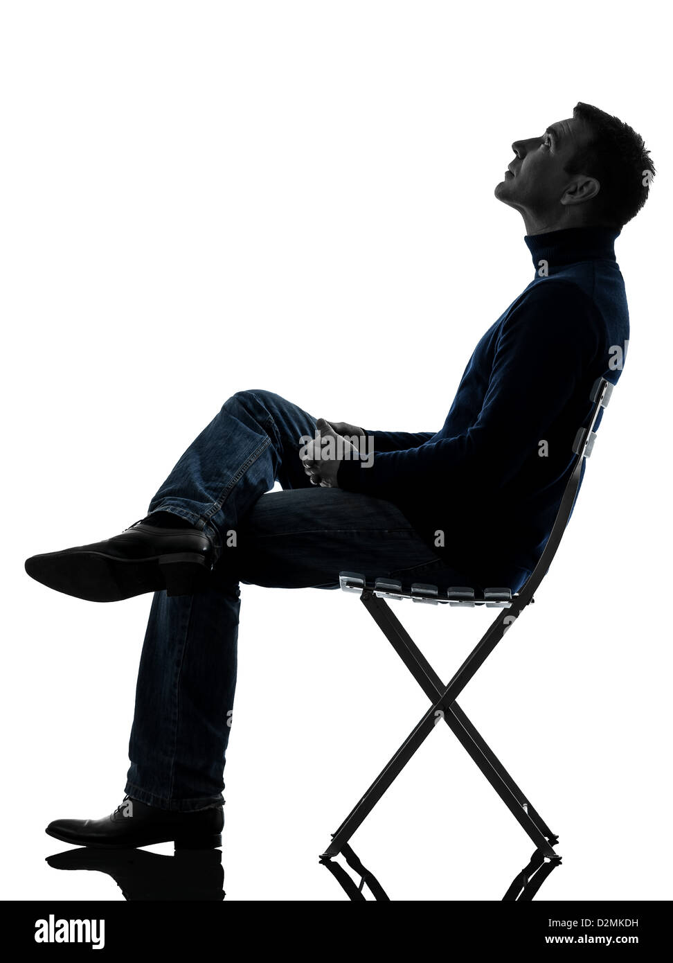 Un homme assis à la pleine longueur jusqu'en silhouette studio isolé sur fond blanc Banque D'Images