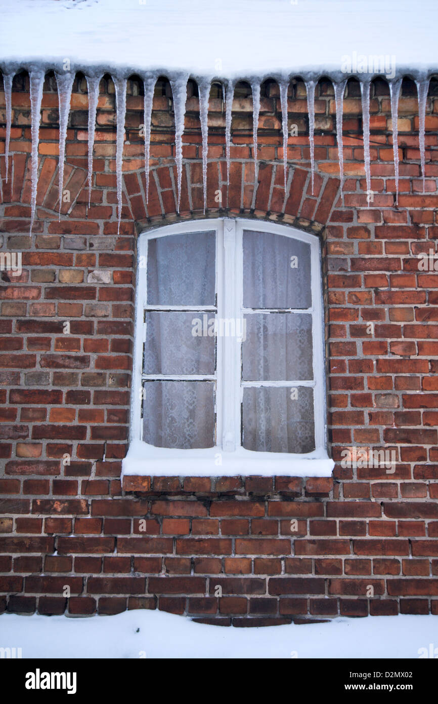 Gros glaçons qui descendent du toit d'une belle vieille brique maison polonaise rural Banque D'Images