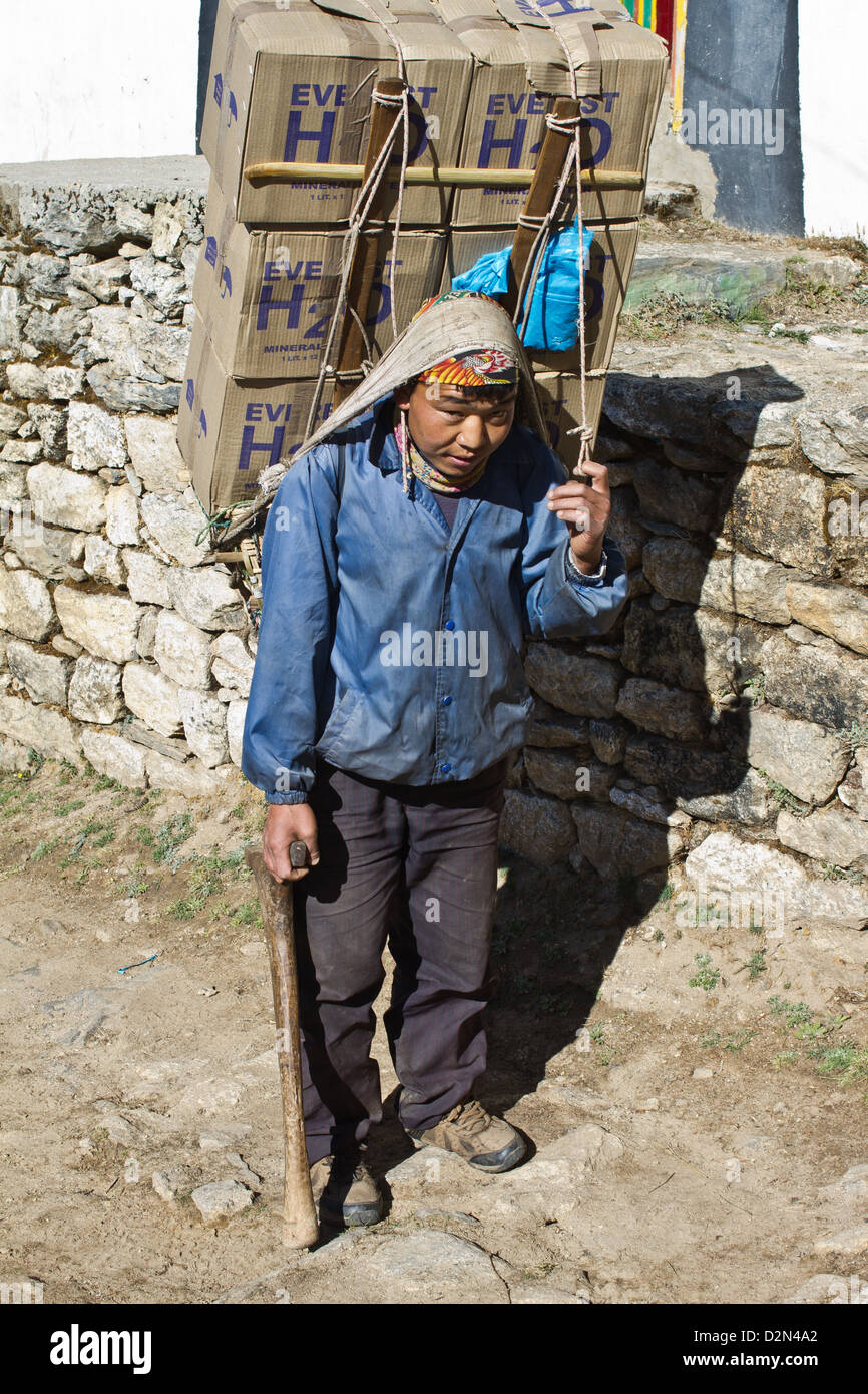Un jeune porteur de transporter l'eau sur le sentier du mont Everest en Asie Népal Khumbu Banque D'Images