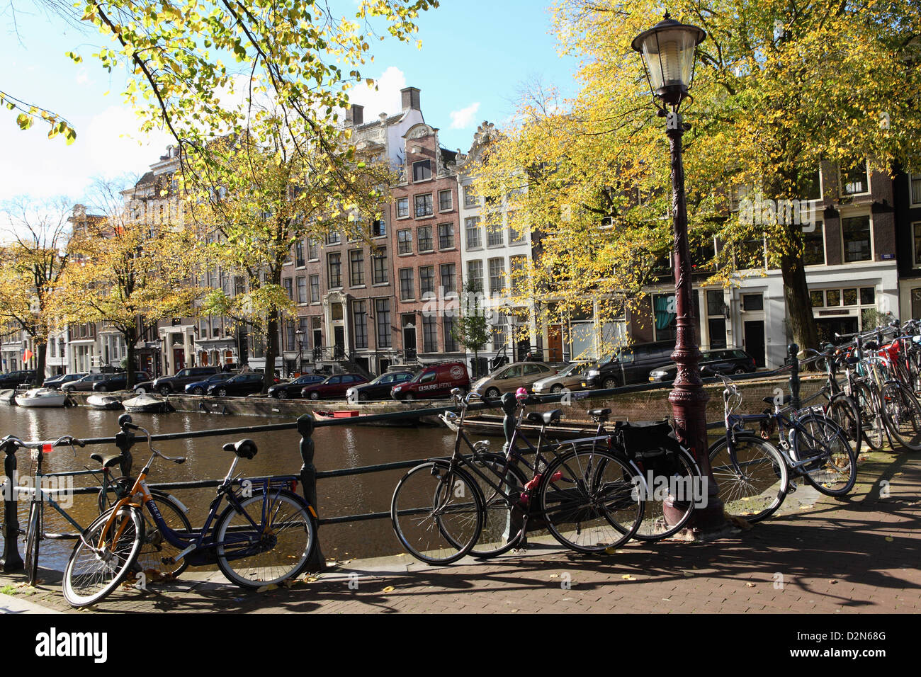 Les vélos enchaînés à des garde-corps par un canal sur une journée ensoleillée à Amsterdam, Pays-Bas, Europe Banque D'Images