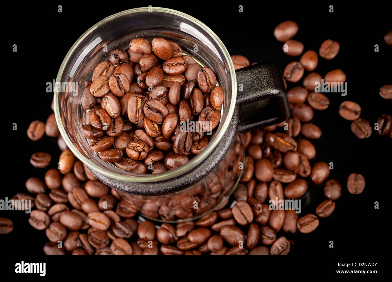 Mug moderne en verre avec les grains de café sur fond noir Banque D'Images