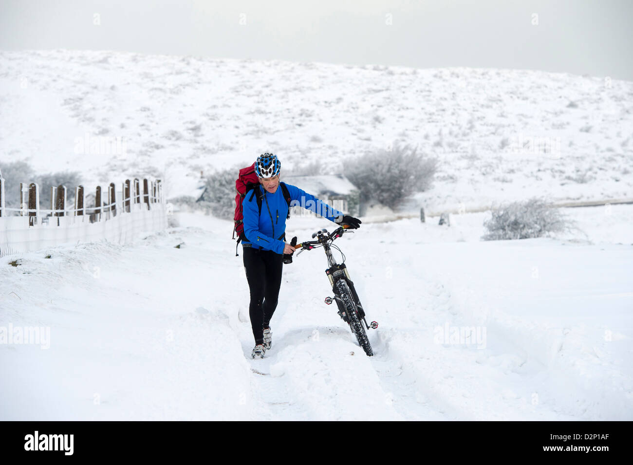 Un brave cycliste pousse son vélo dans la neige sur l'A39 qui est bloqué en raison de la neige des ravages sur Somerset Devon frontière, UK Banque D'Images