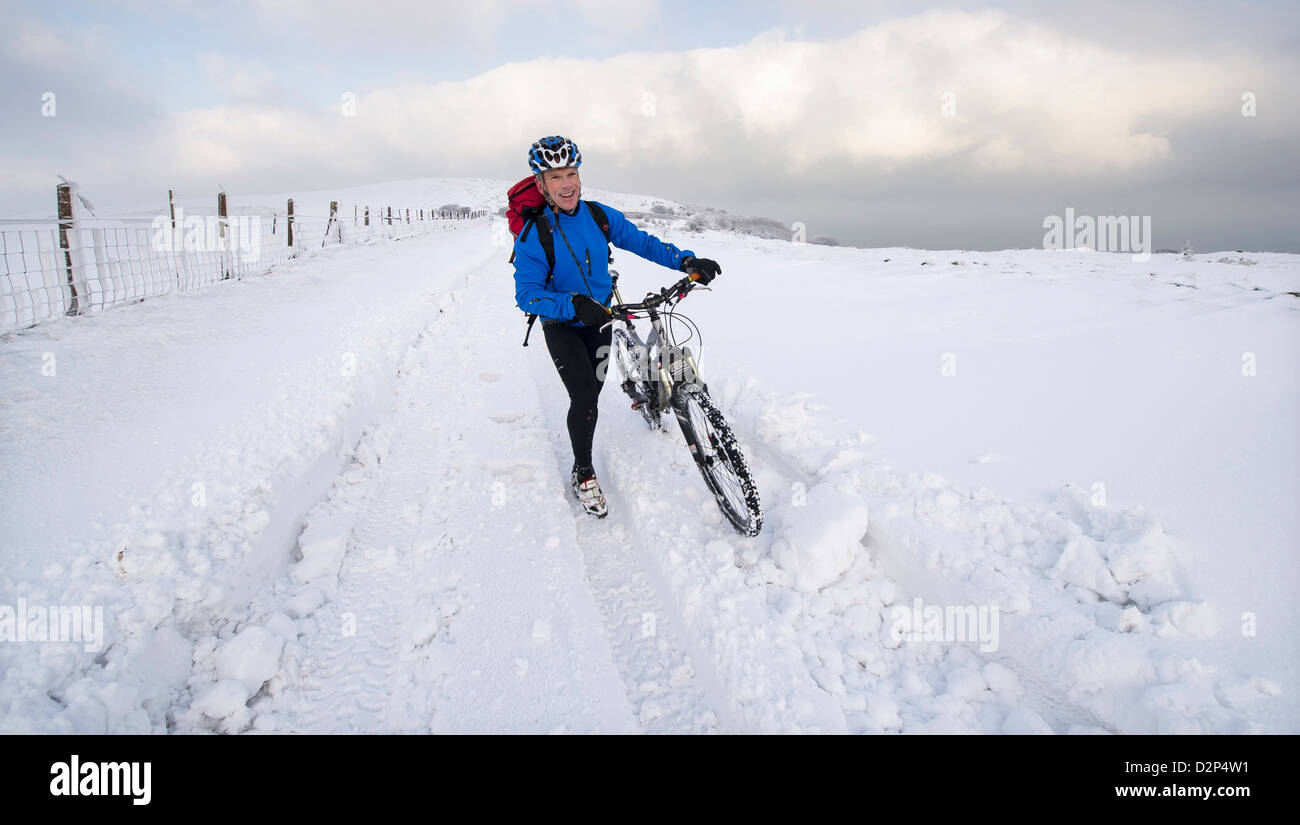 Un brave cycliste pousse son vélo dans la neige sur l'A39 qui est bloqué en raison de la neige des ravages sur Somerset Devon frontière, UK Banque D'Images