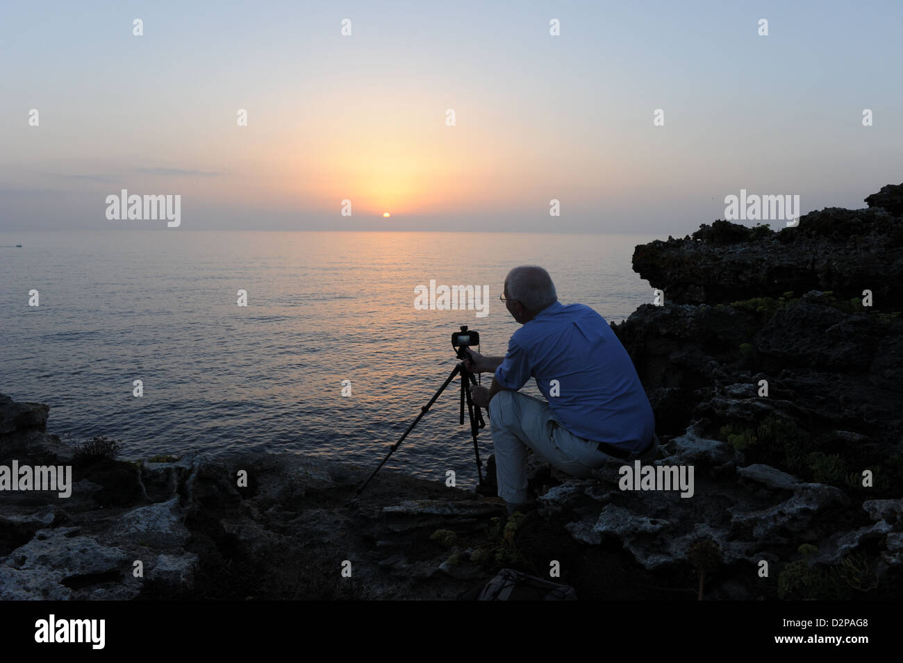 Silhouette d'un photographe à prendre des photos en utilisant un trépied à l'aube sur la côte de Minorque, Iles Baléares, Espagne Banque D'Images