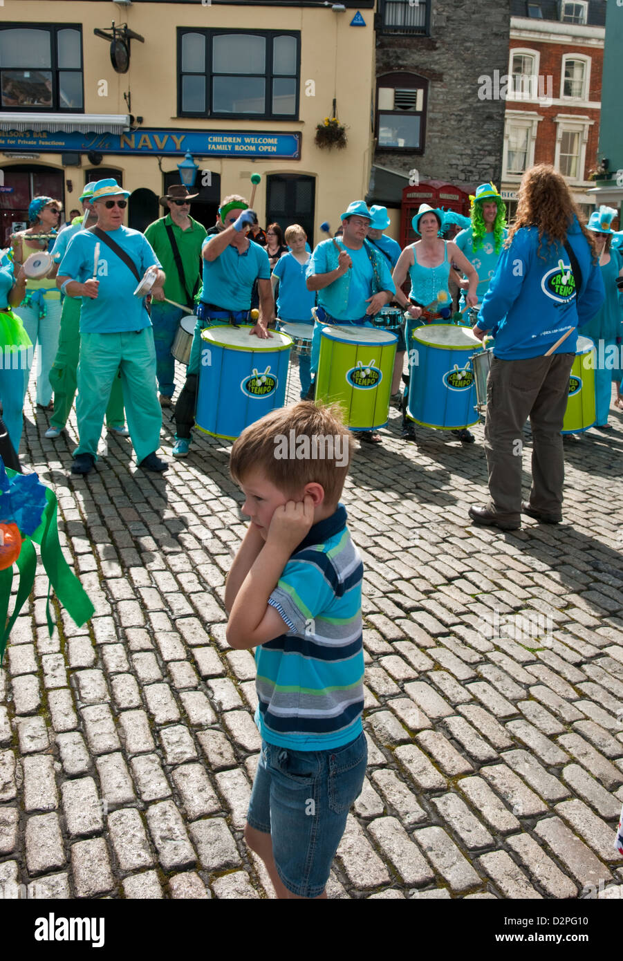Un enfant en passant par une bande de tambour avec les doigts dans ses oreilles Banque D'Images