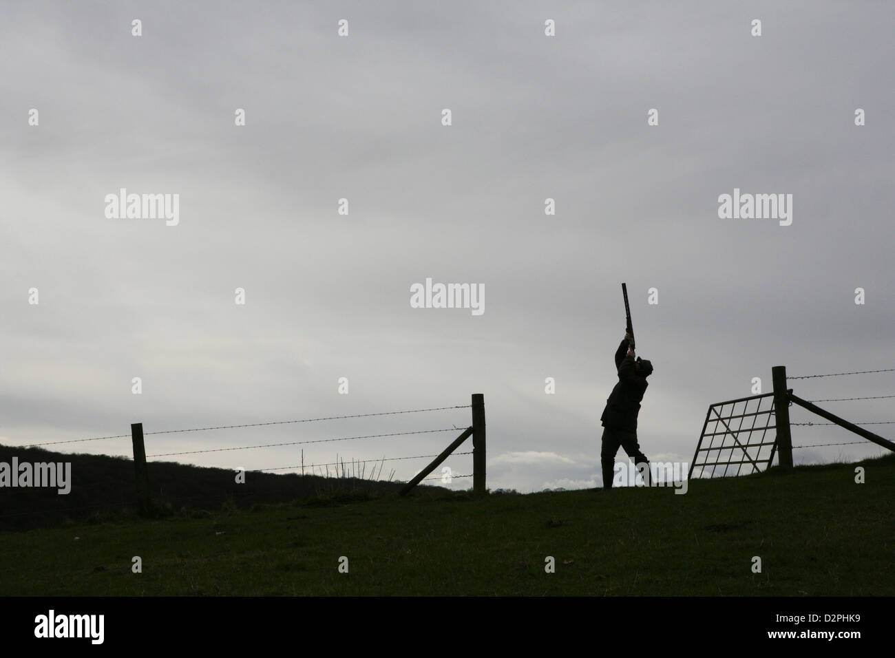 Silhouette d'un homme d'abattre un shot gun. Banque D'Images