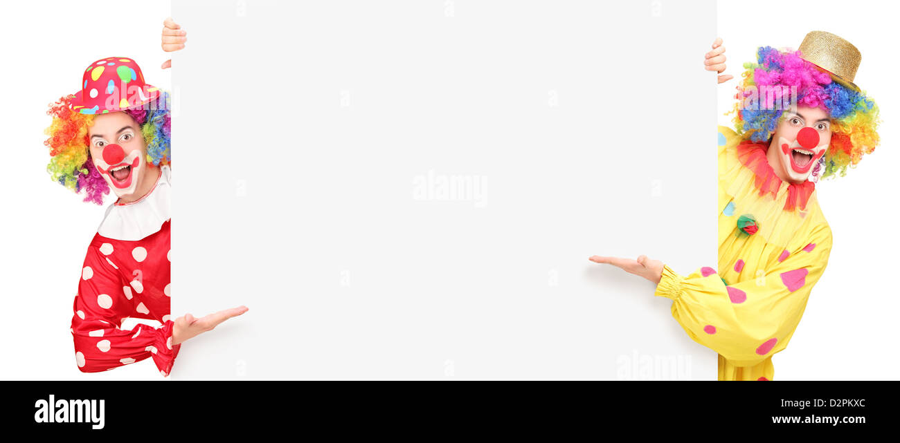 Funny clowns de cirque posant derrière un panneau vierge et gesticulant isolé sur fond blanc Banque D'Images