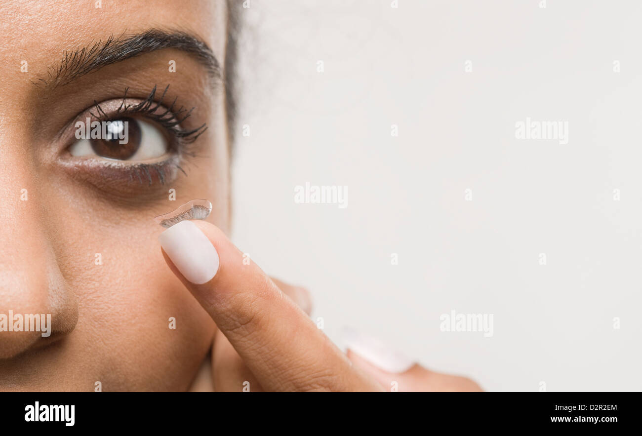 Woman putting on contact lens Banque D'Images
