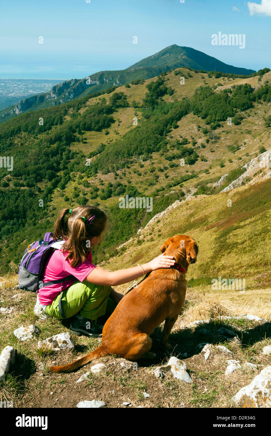 Girl and dog, looking at view de Camaiore et la mer Tyrrhénienne à partir de Alpes Apuanes (Alpes Apuanes), la province de Lucques, Toscane, Italie Banque D'Images