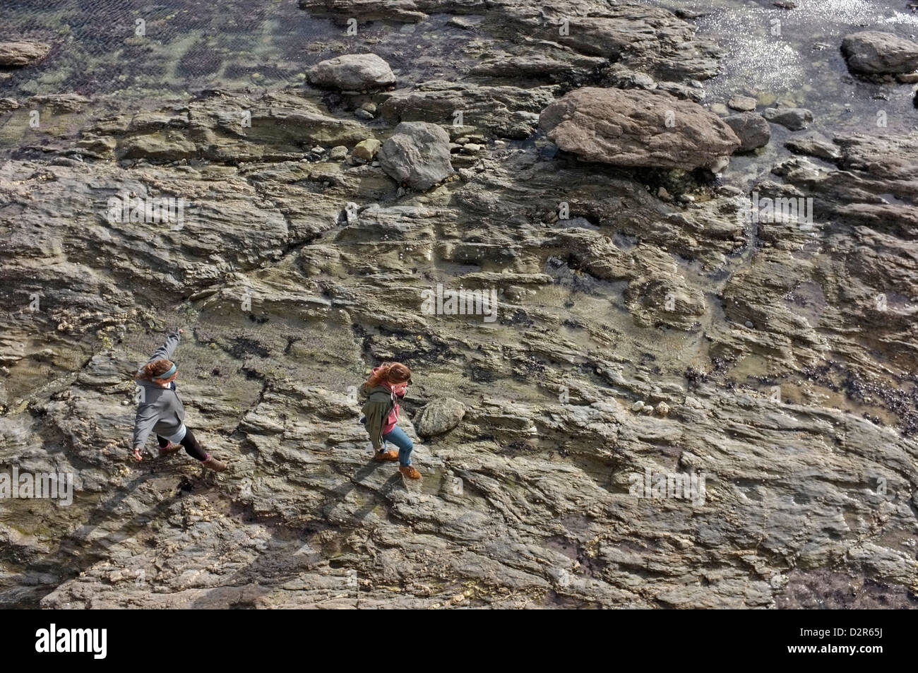Deux jeunes femmes à pied le long des rochers sur la plage de Gyllingvase à Falmouth, Cornwall Banque D'Images