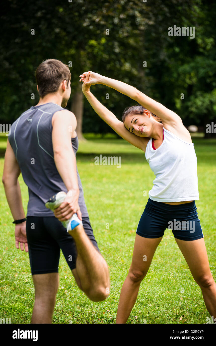 Jeune couple l'exercice et les étirements muscles avant l'activité sportive - piscine dans la nature Banque D'Images