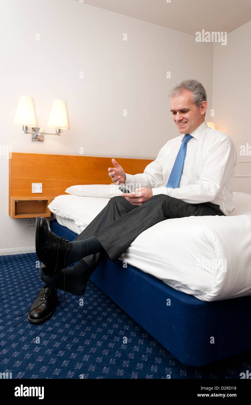 Les voyageurs d'enlever des chaussures dans chambre d'hôtel alors qu'phone. Banque D'Images