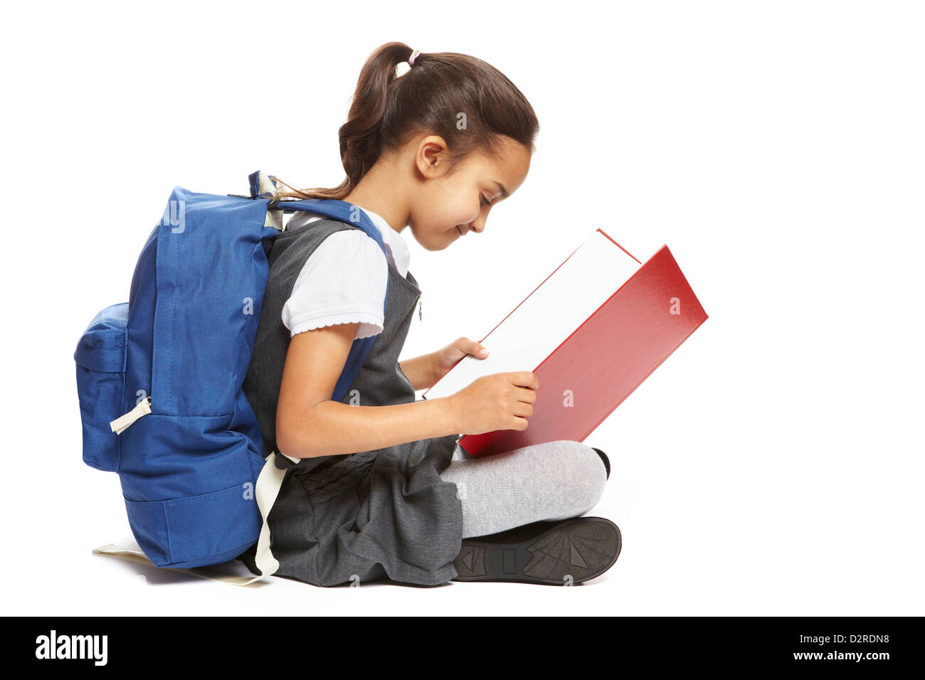 8 ans fille de l'école en train de lire livre avec sac à dos smiling on white background Banque D'Images