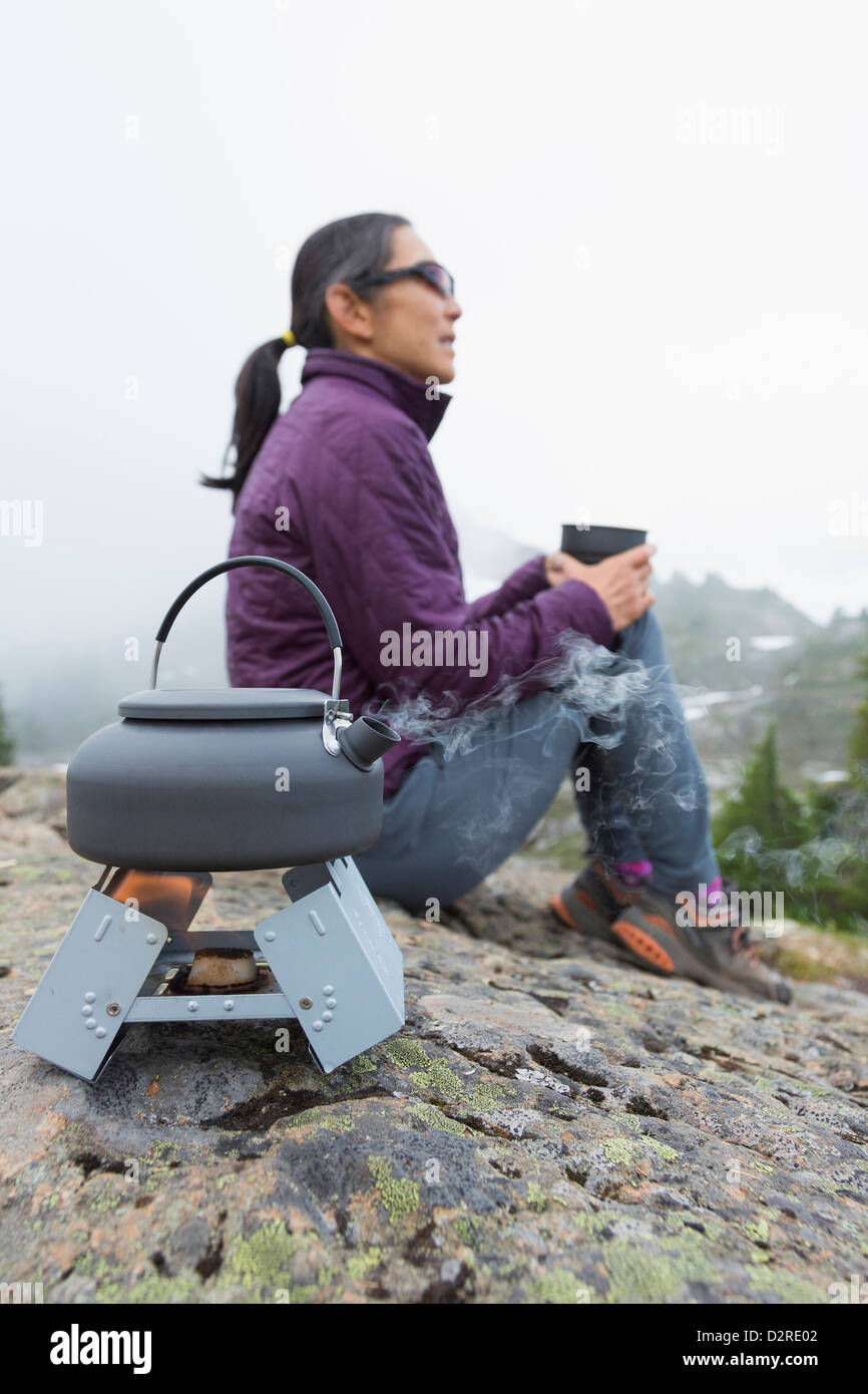 Japanese woman drinking coffee at campsite Banque D'Images