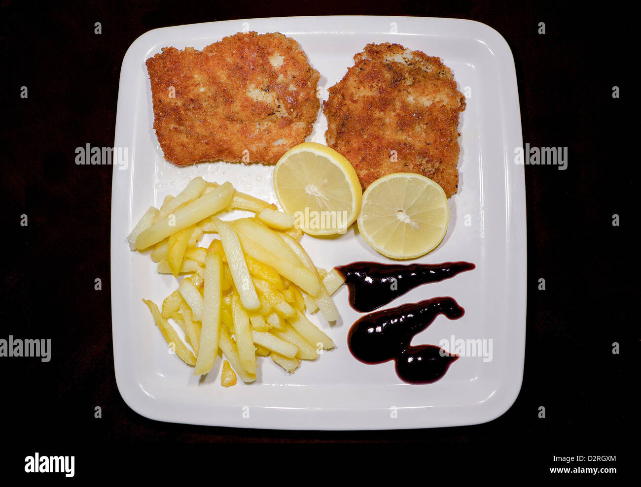 Fish, chips, le citron et la vinaigrette dans une assiette blanche Banque D'Images