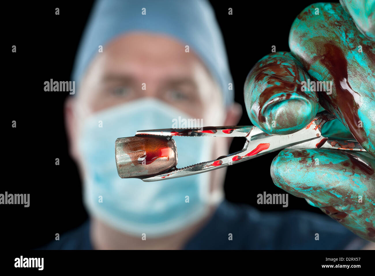 Un chirurgien est titulaire d'une sanglante bullet avec une paire de pinces de serrage. Banque D'Images