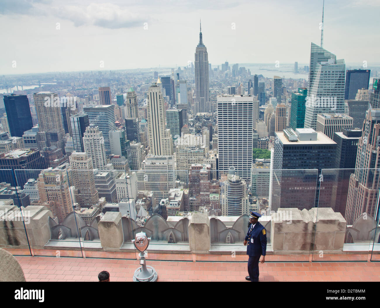 Manhattan, New York. Un garde sur le 'Top of the Rock", la célèbre terrasse d'observation. L'Empire State Building en arrière-plan. Banque D'Images