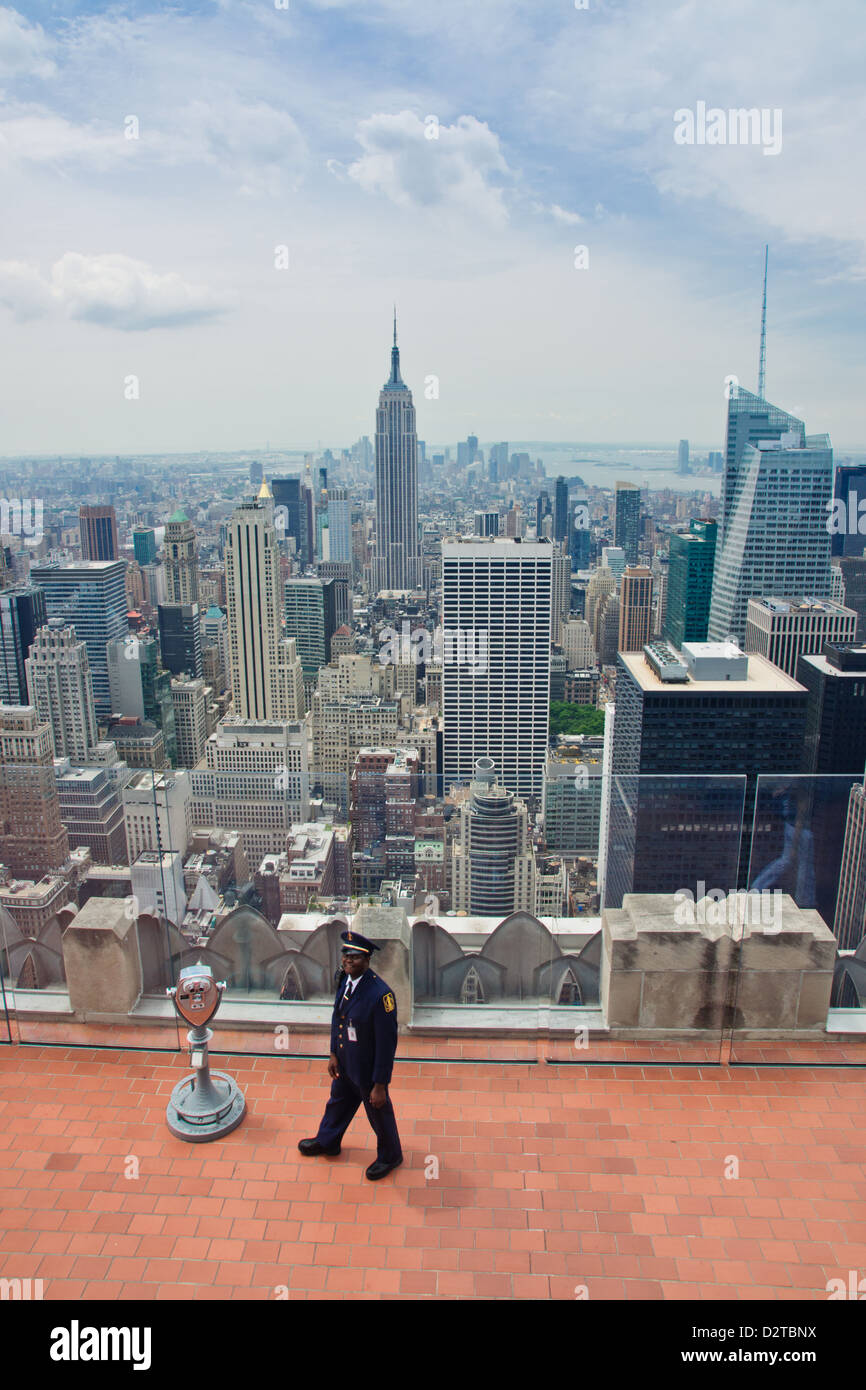 Manhattan, New York. Un garde sur le 'Top of the Rock", la célèbre terrasse d'observation. L'Empire State Building en arrière-plan. Banque D'Images