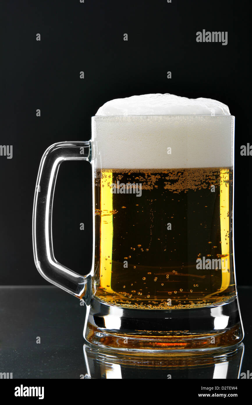 Chope de bière avec de l'écume sur fond noir Banque D'Images
