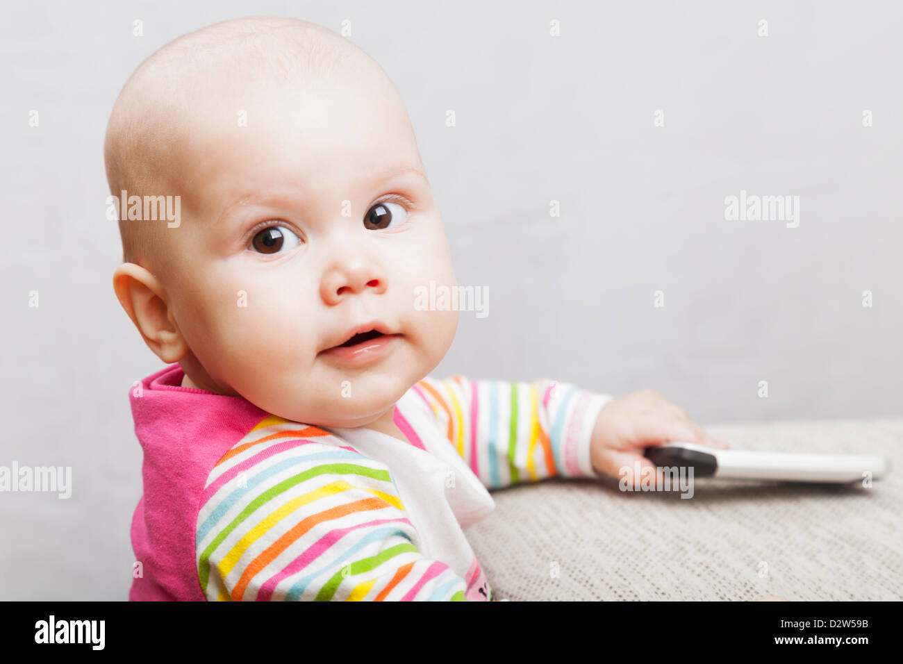 Petit bébé dans des vêtements à rayures occasionnels avec téléphone mobile et sourit Banque D'Images